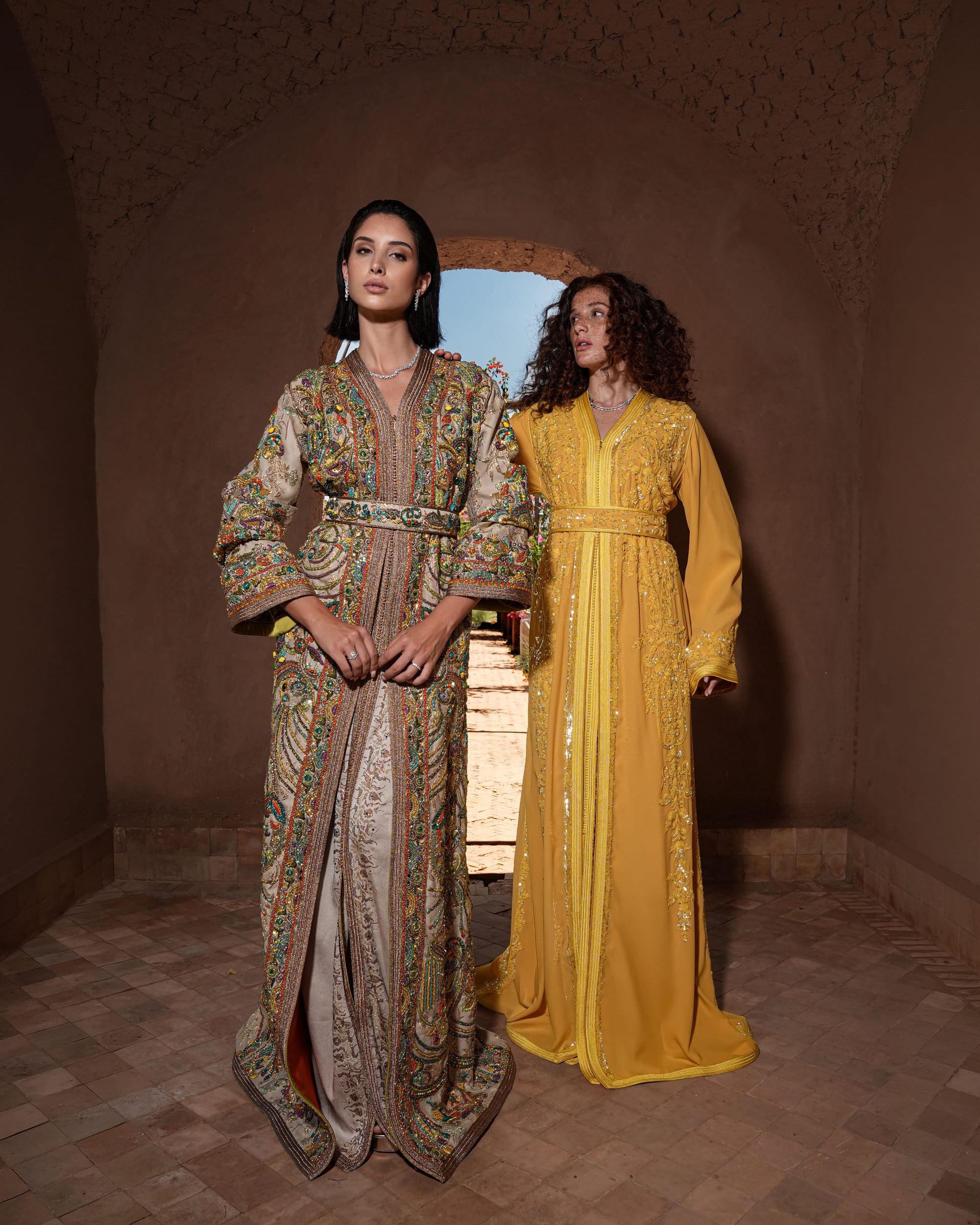 Mosaic Alcove beige silk Moroccan kaftan with polychrome beaded paisley embroidery in a Persian garden motif, shown alongside a second look